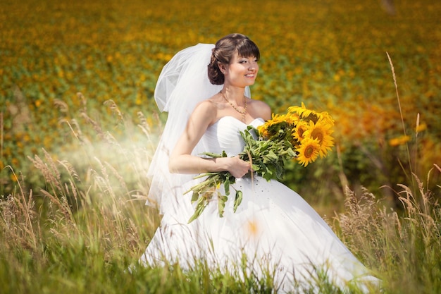 Schoonheid bruid in veld met boeket van zonnebloemen