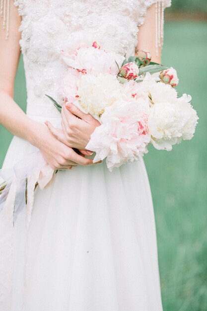 Schoonheid bruiloft boeket van roze en witte pioenroos bloemen in handen van de bruid.