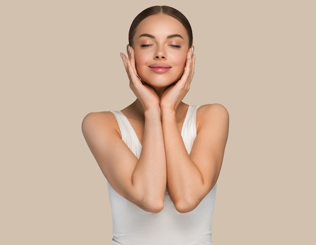 Schoonheid gezonde huid vrouwen aanraken van gezicht cosmetische studio portret. Sportkleding kleur achtergrond bruin