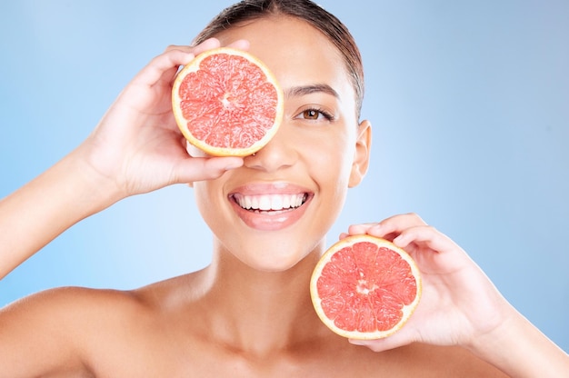 Schoonheid grapefruit en vrouw met gezicht en natuurlijke cosmetische verzorging gezichts- en gloed met veganistisch product tegen studio achtergrond Huidverzorging gezonde huid en wellness met fruithanden en cosmetica