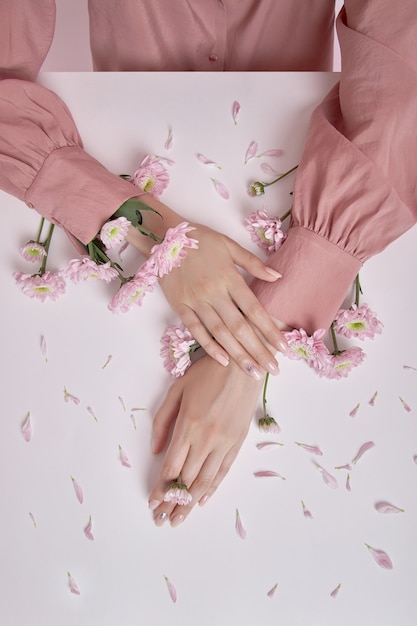 Schoonheid handen vrouw met roze bloemen liggen op tafel.