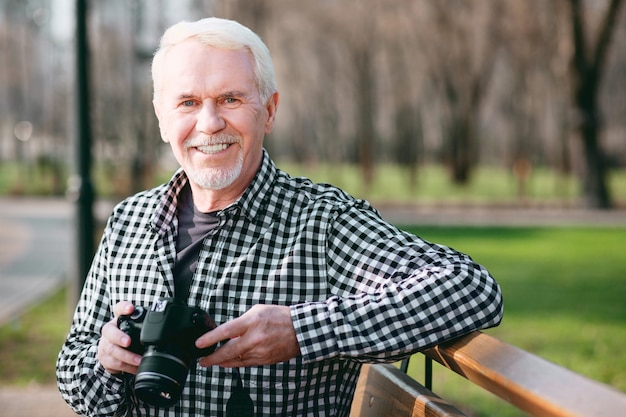 Foto schoonheid in foto's. energieke volwassen man met behulp van camera en grijnzend naar de camera