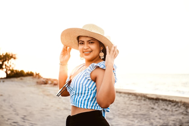 Schoonheid jonge vrouw met beugels die een hoed op het strand dragen