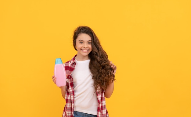 Schoonheid kind gebruik douchegel gelukkig tiener meisje met shampoofles shamponeren haar in salon