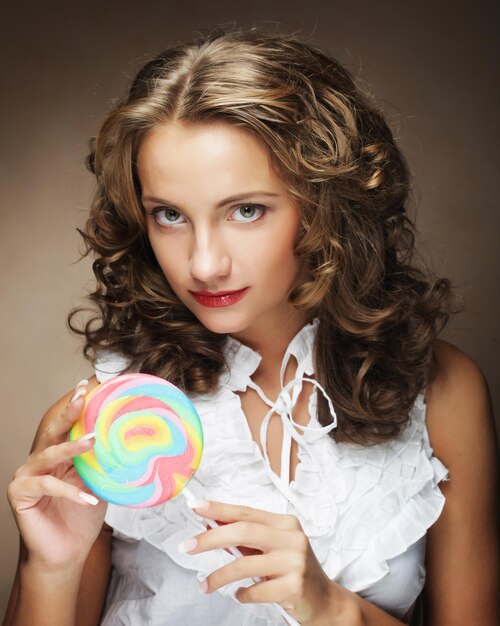 Schoonheid krullend meisje portret met kleurrijke lolly