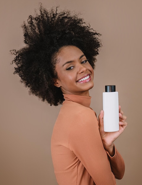 Schoonheid Latijnse vrouw met afro kapsel Braziliaanse vrouw Holding lege shampoo verpakking