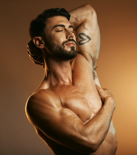 Schoonheid lichaam fitness en man in studio geïsoleerd op een bruine achtergrond Ogen gesloten oefening en topless mannelijk model of bodybuilder met spieren die zich tevreden voelen na training voor gezondheid of welzijn