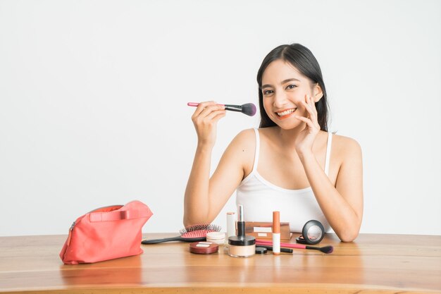 Schoonheid make-up Aziatische vrouw lachend close-up. Mooie jonge vrouw foundation poeder toe te passen of blozen met make-up borstel. Aziatisch Kaukasisch model van gemengd ras.