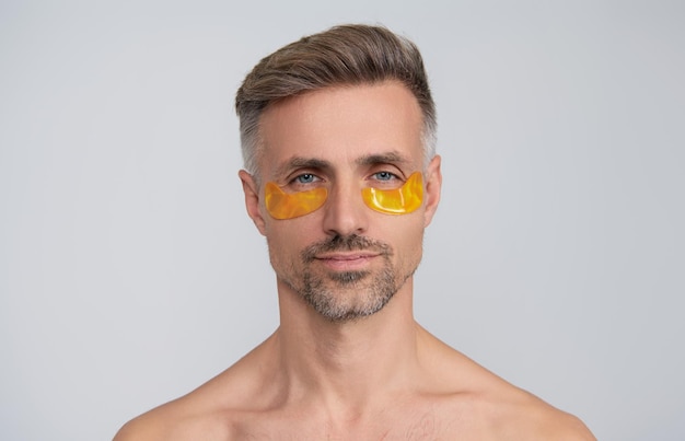 Schoonheid man gezicht met onder de ogen collageen pads Volwassen man heeft frisse gezonde huid met collageen patches onder de ogen gezichtsbehandeling Man het aanbrengen van oog patches Spa zorg oog patch Aanbrengen na een lange dag