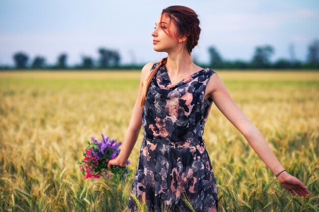 Schoonheid meisje buiten genieten van de natuur. Mooi tienermodel meisje in jurk op het veld van de lente