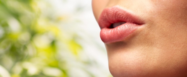 schoonheid, mensen, make-up en plastische chirurgie concept - close-up van jonge vrouw lippen over groene natuurlijke achtergrond