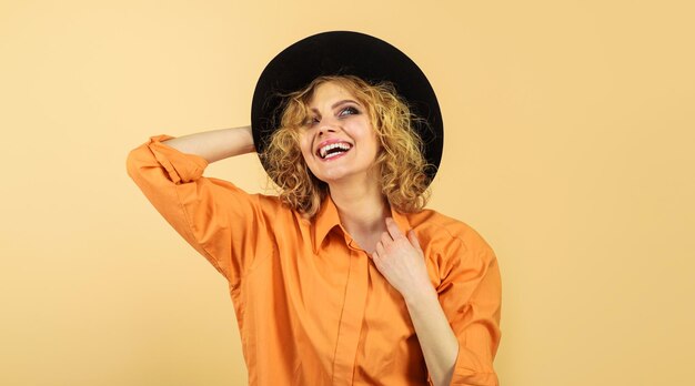 Schoonheid mode vrouwelijke accessoires lachende vrouw in oranje stijlvol shirt en zwarte hoed vrouwelijke herfst