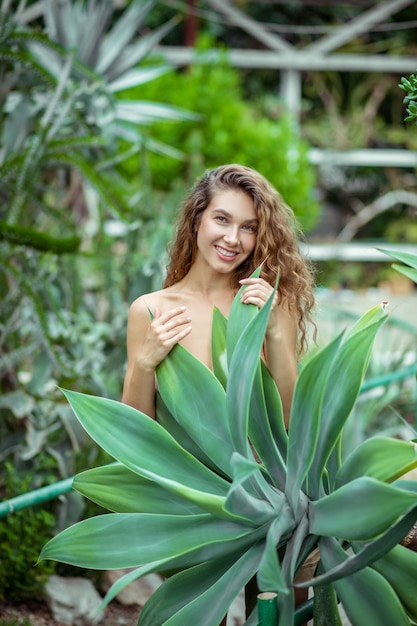 Schoonheid. Naakte vrouw die zich dichtbij de plant bevindt en glimlacht