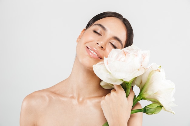 Schoonheid portret van een aantrekkelijke sensuele gezonde vrouw geïsoleerd over witte muur, poseren met een bloem