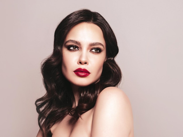 Schoonheid portret van jonge brunette vrouw met avond make-up en perfecte schone huid Sexy model met krullend haar poseren in studio met rode heldere natuurlijke lippen