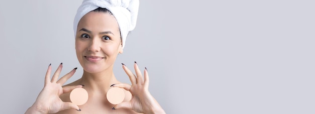Schoonheid portret van vrouw in witte handdoek op hoofd met een spons voor een lichaam met het oog op een roze hart Huidverzorging reiniging eco organische cosmetische spa ontspannen concept