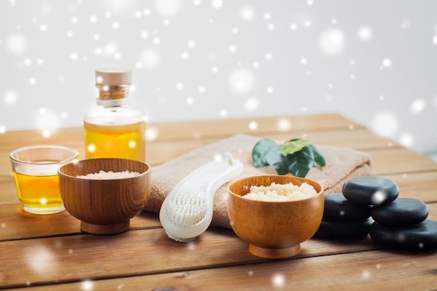 schoonheid, spa, lichaamsverzorging, natuurlijke cosmetica en massageconcept - bodyscrub met borstel en massageolie op houten tafel over sneeuw