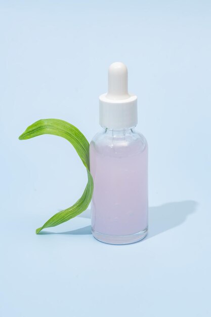 schoonheid spa medische huidverzorging en cosmetische serum fles verpakking op blauwe achtergrond met groen blad gezond en medicijn concept