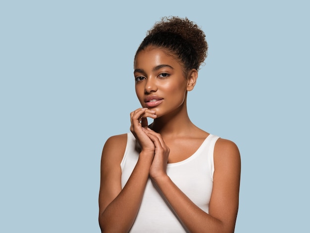 Schoonheid vrouw zwarte huid gezicht glimlachend model wat betreft haar gezicht. Kleur achtergrond. Blauw