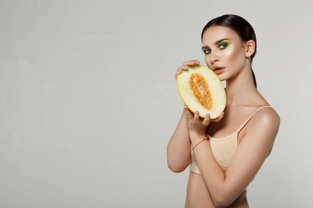 Schoonheid vrouwelijk model dat sappige meloenplak toont bij camera