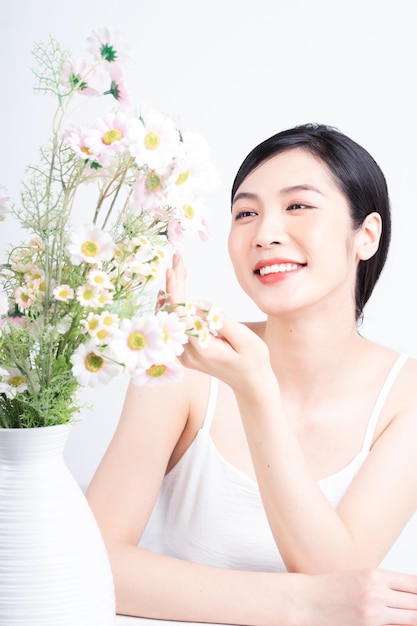 Schoonheidsbeeld van jonge Aziatische vrouw met bloemen