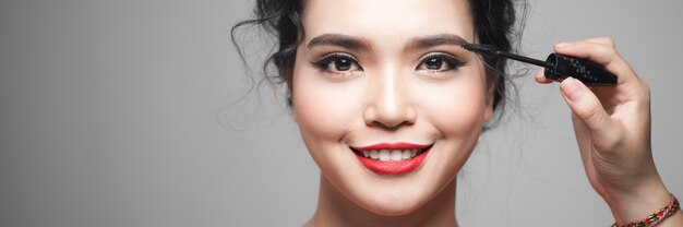 Schoonheidsconcept, aziatische vrouw met gesloten ogen die mascara in de buurt van de ogen houdt