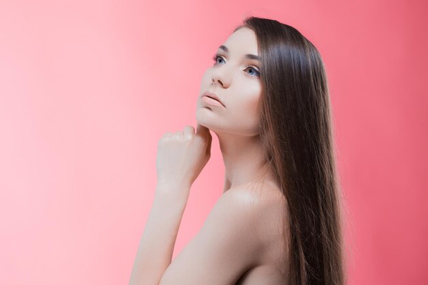 Foto schoonheidsportret van brunette met perfect haar op een roze achtergrond
