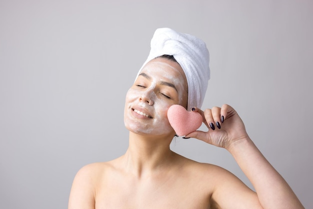 Schoonheidsportret van een vrouw in een witte handdoek op het hoofd brengt crème aan op het gezicht Huidverzorgingsreiniging