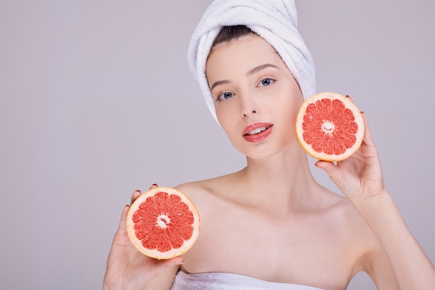 Schoonheidsportret van een vrouw met grapefruit dichtbij het gezicht.