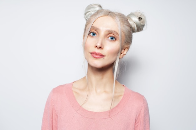 Schoonheidsportret van mooi blond meisje met blauwe ogen en haarbroodjes op wit