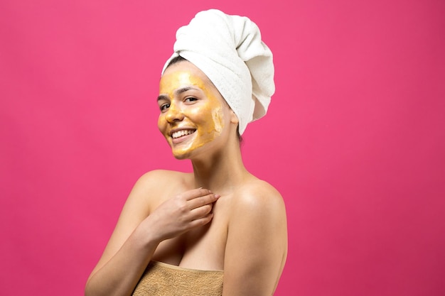 Schoonheidsportret van vrouw in witte handdoek op hoofd met gouden voedend masker op gezicht Huidverzorging reinigende eco organische cosmetische spa ontspannen concept