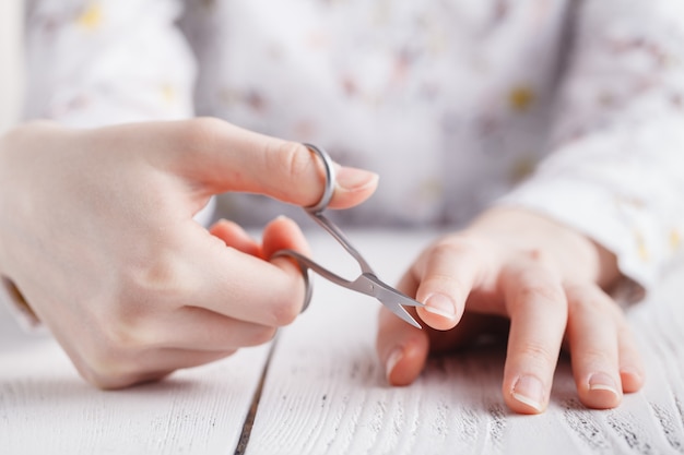 Schoonheidssalon, manicure aanbrengen, knippen van de nagelriem met een schaar