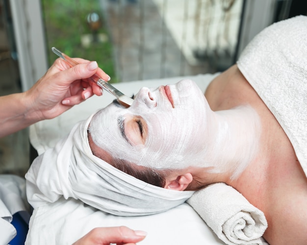 Schoonheidsspecialist gezichtsmasker toe te passen op het gezicht van de vrouw met stok