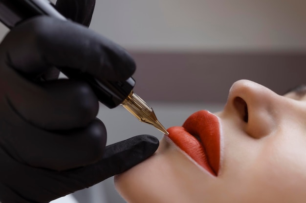 Schoonheidsspecialist maakt permanente make-up op het gezicht van een vrouw39s Specialist brengt een tatoeage aan op de lippenclose-up van de patiënt39