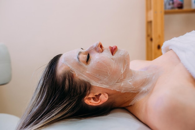 Schoonheidsspecialist maakt reinigende peeling en gezichtsmasker voor vrouw Schoonheid huidverzorging
