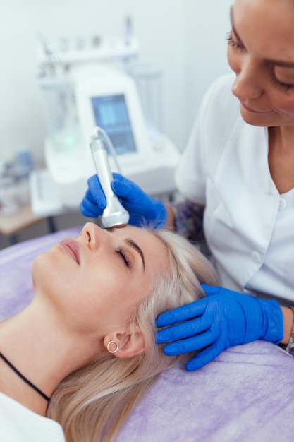 Schoonheidsspecialist maken van apparaten phonophoresis facail procedure voor vrouw in schoonheidssalon