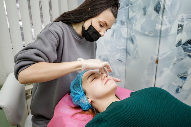 Schoonheidsspecialist masseert het gezicht van een jong meisje na de peelingprocedure.