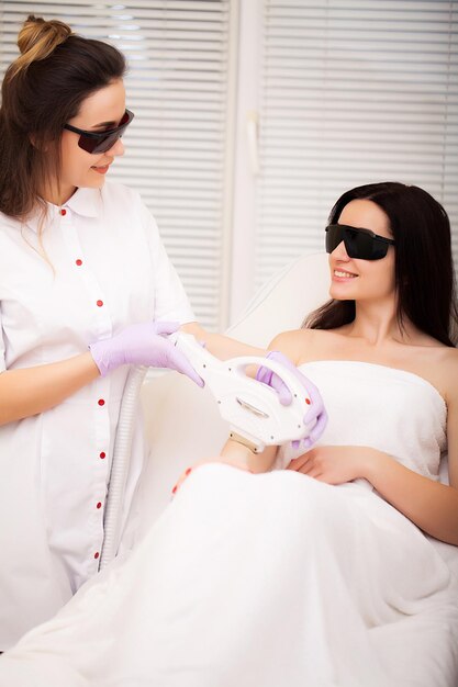 Schoonheidsspecialiste die haar van jonge vrouw verwijdert Laserepilatiebehandeling in cosmetische schoonheidskliniek