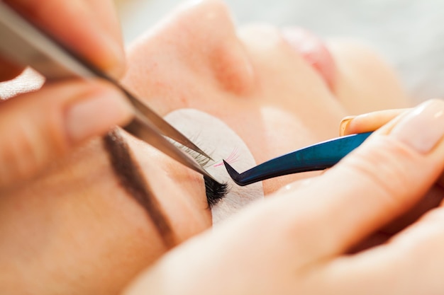 Schoonheidsspecialiste die kunstmatige wimpers maakt Wimperverlenging procedure concept