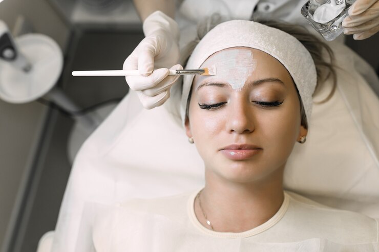 schoonheidsspecialiste past cosmetisch product toe op geduldige vrouw met borstel