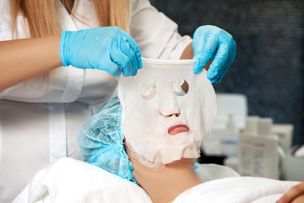 Schoonheidsspecialiste past gezichtsmasker op vrouw toe