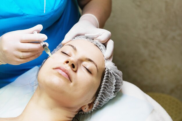 Schoonheidsspecialiste voert een naaldmesotherapiebehandeling uit op het gezicht van een vrouw