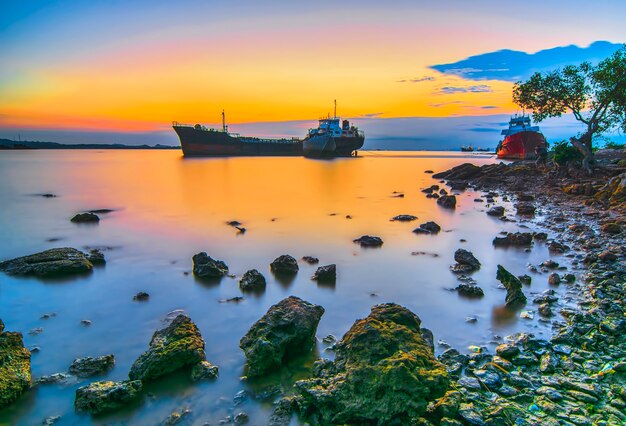 Schoonheidszonsondergang en schip op het strand van Tanjung Pinggir