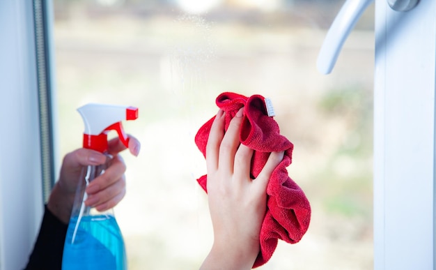 Schoonmaakconcept Jonge vrouw wast raam met spons