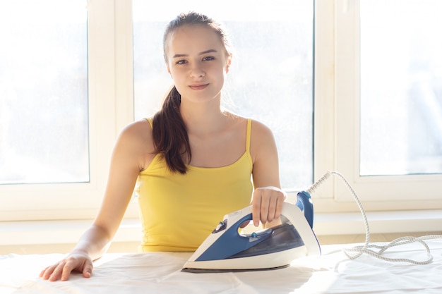 Schoonmaakdienst. Blij jonge vrouw streelde ondergoed. Schattige huishoudster zorgt voor kleding