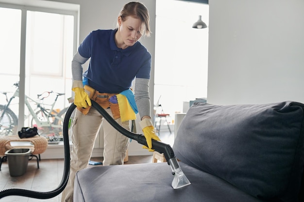 Schoonmaakmedewerker die de bank stofzuigt