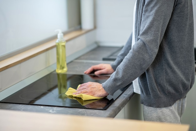 Schoonmaken. Close-up foto van een man die het oppervlak van de tafel in de keuken schoonmaakt