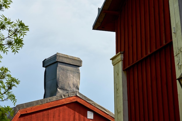 Schoorsteen op een oud houten huis met een bewolkte lucht op de achtergrond