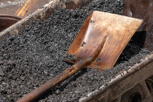 Schop werd gelegd op het asfalt voorbereid voor reparaties aan de weg.