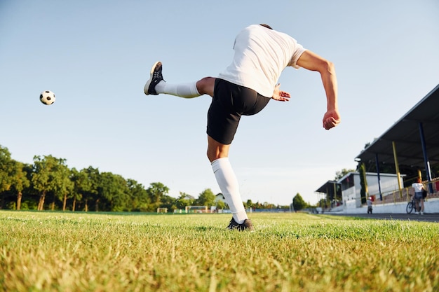 Schopt de bal Jonge voetballer heeft training op het sportieve veld